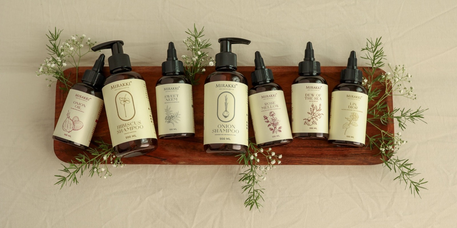 Mirakki botanical hair oils and wash care arranged with fresh sprigs